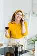 © LIGHTFIELD STUDIOS - woman talking by smartphone and drinking wine in kitchen