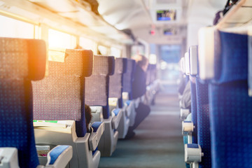 Interior of modern intercity express train. Back view of  wide comfortable seats in row at  railroad transport. Sunrise light through window