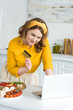 © LIGHTFIELD STUDIOS - smiling beautiful woman holding credit card and looking at laptop at kitchen