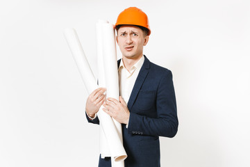 Irritated dissatisfied businessman in dark suit, protective construction orange helmet holding blueprints plans isolated on white background. Male worker for advertisement. Business, working concept.