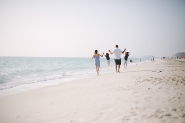 Family with Young Boys Holding Hands and Walking Down the Coastline at the Beach