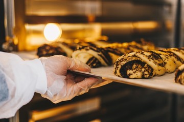 Baker puts a baking sheet with baking in the oven