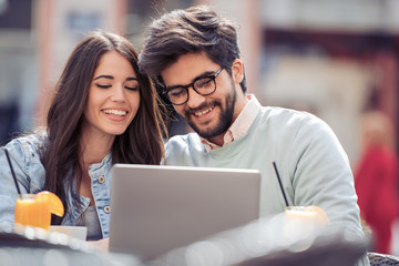 Canvas Print - Happy couple at coffee shop using laptop