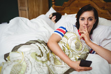 Portrait Of Woman Using Mobile Phone With Finger On Lips