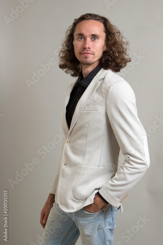 Guy With Long Curly Hair Businessman In A White Jacket On A Gray