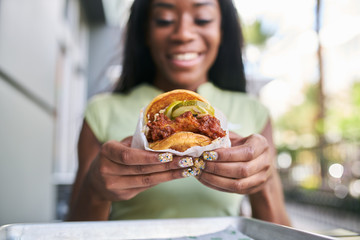 african american woman holding nashville hot chicken sandwich