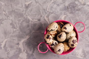 Sticker - One pink metal rural basin with handles full of spotted fresh quail eggs on old broken worn gray cement floor with copy space