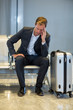 © Wavebreak Media - Tense businessman sitting in waiting area with luggage
