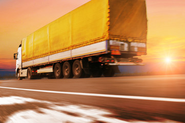 Sticker - Truck with the trailer driving fast on the countryside road with snow against sky with sunset