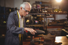Senior Cobbler Repairing Shoe In Workshop