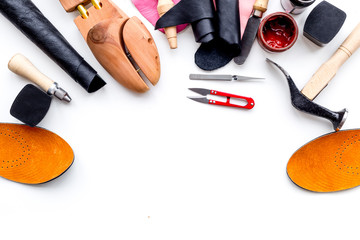 Wall Mural - Work desk of shoemaker with instruments, wooden shoe and leather. White background top view copy space