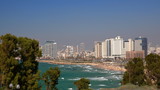 Fototapeta  - Widok na zatokę Morza śródziemnego w Tel Awiwie, Izrael, z piaszczystą plażą i nowoczesnymi wysokimi budynkami na nabrzeżu, na pierwszym planie drzewa  w parku w Hajfie, fale na szmaragdowej wodzie