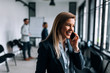 © bnenin - Portrait of a smiling blonde businesswoman talking on a phone during the break from a meeting.