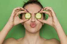 Sexy Young Woman Posing With Slices Of Cucumber On Her Face On Green Background