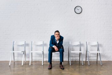 Wall Mural - Businessman sitting on chair and leaning on his knees