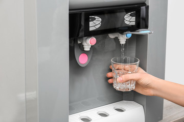 Canvas Print - Woman filling glass from water cooler, closeup