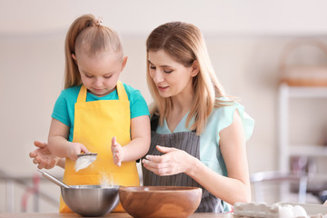 Wall Mural - Mother with daughter sifting flour in kitchen