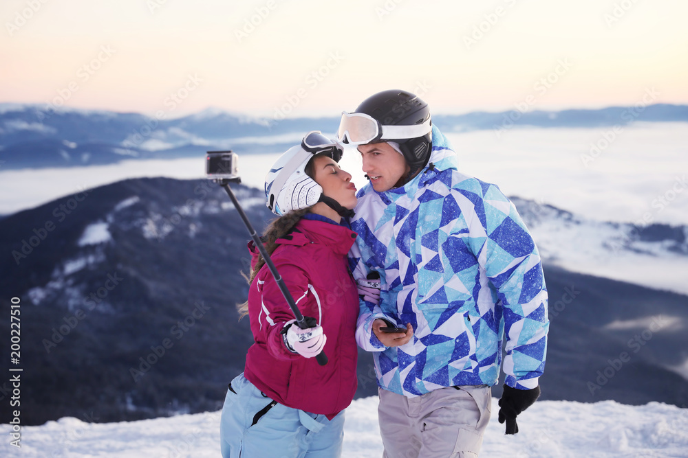 Couple taking selfie at snowy ski resort. Winter vacation