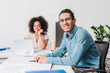 © LIGHTFIELD STUDIOS - Young man in eyeglasses sitting in office by female colleague