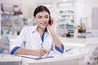 © Viacheslav Yakobchuk - Business talk. Optimistic female pharmacist making call while taking notes