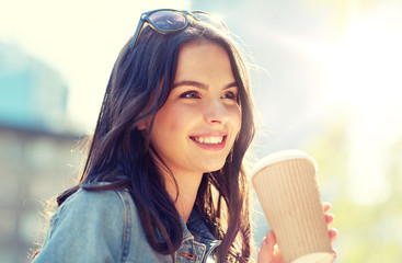 Wall Mural - drinks and people concept - happy young woman or teenage girl drinking coffee from paper cup on city street