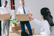 © LIGHTFIELD STUDIOS - businesswoman showing thumb up to male colleagues holding cardboard boxes in new office