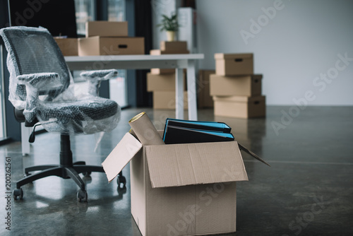Fotografía cardboard box with folders and office supplies in floor during relocation