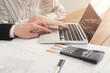 © Prostock-studio - Business colleagues typing on laptop and checking diagrams