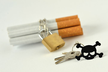 Cigarettes with chain and padlock and key with black skull on white background - Stop smoking concept