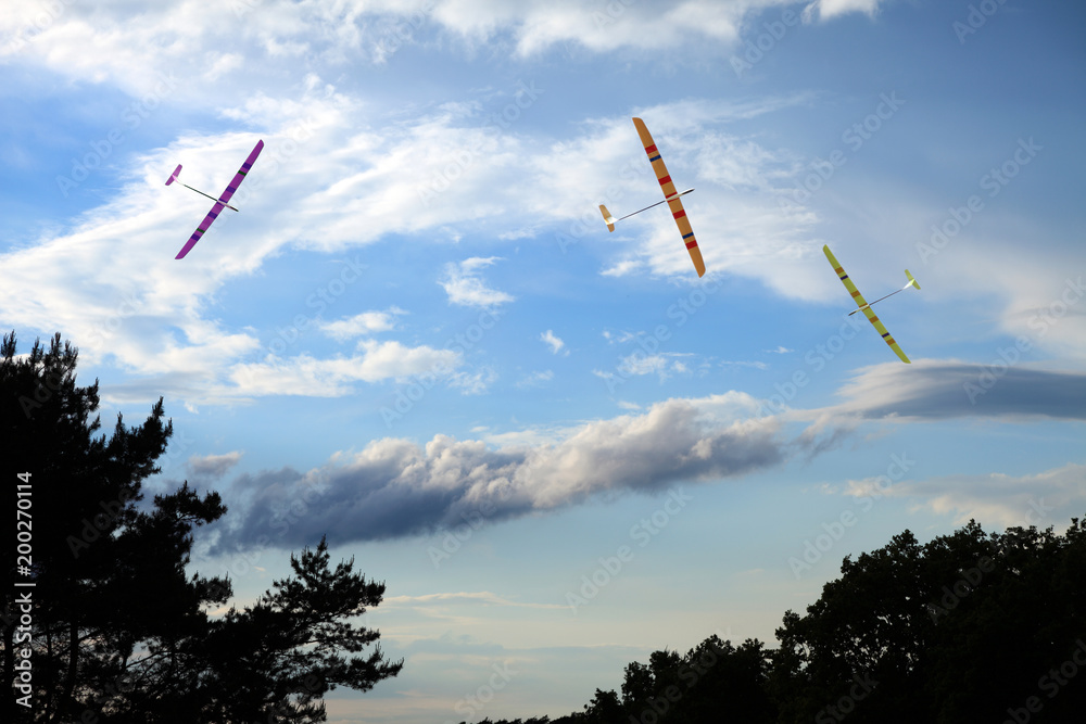 Trzy modele szybowców zdalnie sterowanych na tle błękitnego nieba. - obrazy, fototapety, plakaty 