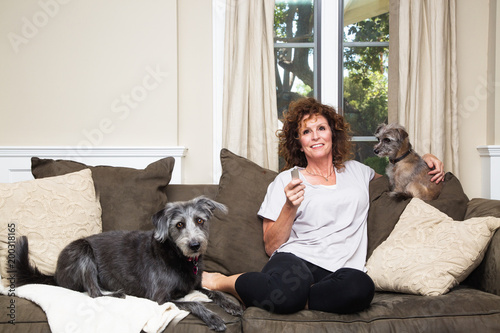 Cuadros en Lienzo Adult Female Watching TV With Dogs on Sofa