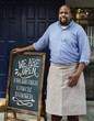 © Rawpixel.com - A cheerful business owner standing with open blackboard