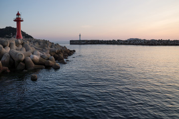 Wall Mural - Lighthouses during dawn at a seawall with wavebreakers in Seogwipo, Jeju Island, South Korea