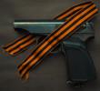 pneumatic pistol with a St. George ribbon on a black background