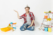 © ViDi Studio - Pretty woman in newspaper hat pointing hand aside on copy space, sit on floor with instruments for renovation apartment isolated on white background. Wallpaper, painting tools. Repair home concept.