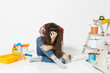 © ViDi Studio - Confused annoyed tired shocked woman sitting on floor with instruments for renovation apartment isolated on white background. Wallpaper, accessories for gluing, painting tools. Concept of repair home.