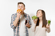 © ViDi Studio - Couple man and woman standing with green detox smoothies, salad in glass bowl, burger, cola in glass bottle isolated on white background. Proper nutrition, healthy lifestyle, fast food, choice concept