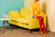 cropped shot of woman in retro clothing on sofa at colorful apartment, doll house concept