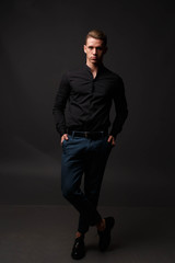 Wall Mural - attractive white man in black shirt and blue pants stands on a dark background