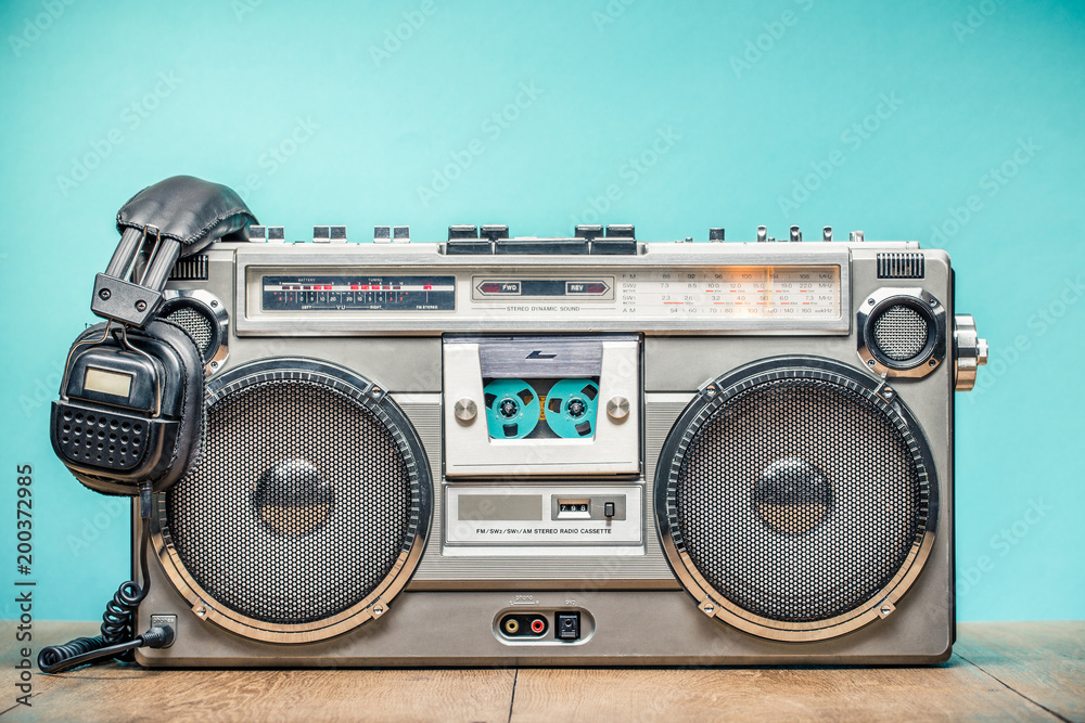Retro outdated portable stereo boombox radio cassette recorder from circa late 70s with aged headphones front aquamarine wall background. Listening music concept. Vintage old style filtered photo - obrazy, fototapety, plakaty 
