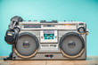 Retro outdated portable stereo boombox radio cassette recorder from circa late 70s with aged headphones front aquamarine wall background. Listening music concept. Vintage old style filtered photo