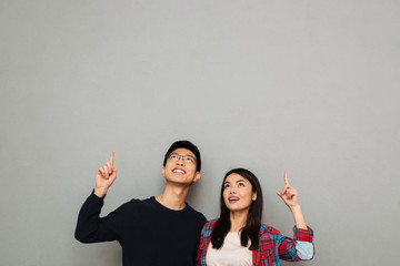 Wall Mural - Excited young asian loving couple pointing.