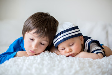 Wall Mural - Cute baby boy, dressed in marine clothes, sleeping with his older brother and little cute baby bunny