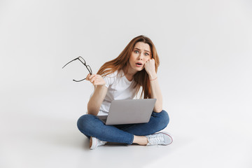 Poster - Shocked confused woman in t-shirt sitting on the floor