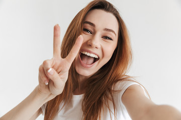 Wall Mural - Woman in casual clothes making selfie while showing peace gesture