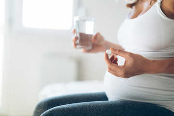 Wall Mural - Picture of pregnant woman taking medication pills