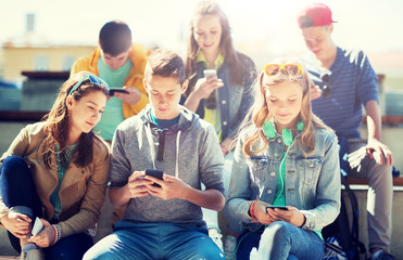 Poster - technology, internet addiction and people concept - happy teenage friends with smartphones outdoors