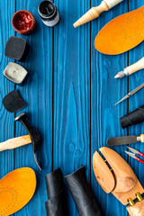 Wall Mural - Instruments and materials for make shoes. Shoemaker's work desk. Hummer, awl, knife, sciccors, wooden shoe, insole, paint and leather. Blue wooden background top view copy space