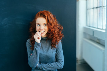 Worried young woman biting her nail in trepidation