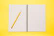 © papii - Open note book blank pages with yellow pencil on yellow background